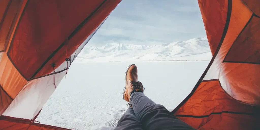 Tent Materials: A hiker during winter with an open tent vestibule to air the tent out