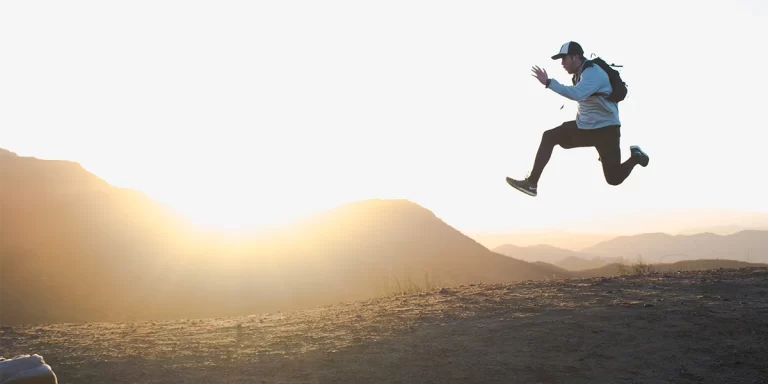 Minimalist Backpacking: An ultralight backpacker jumping with a 30L pack during sunset