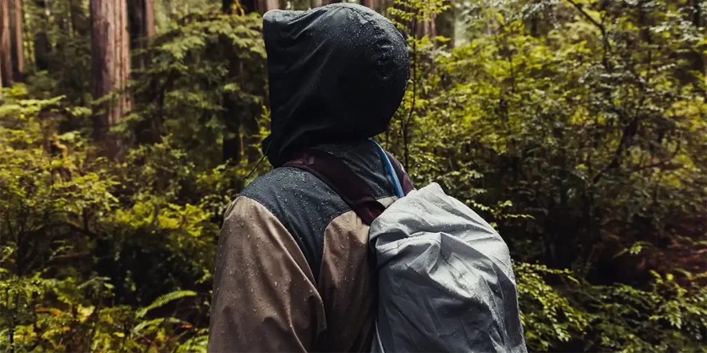 Backpack Rain Covers: Close-up of a backpacker in a rainy forest with a nylon backpack rain cover on their backpack