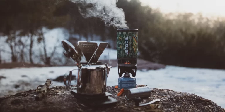 Backpacking Stoves: An ultralight Jetboil canister gas stove in a winter forest clearing