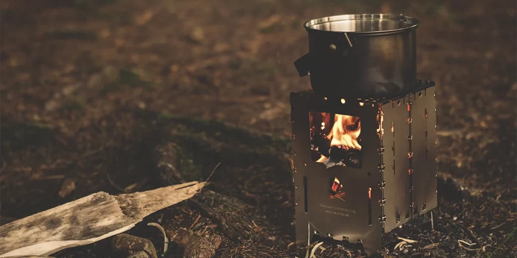 Backpacking wood stove burning at a campsite