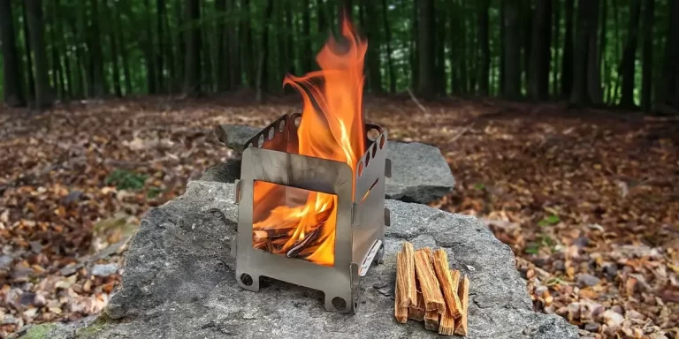 How to Choose a Backpacking Wood Stove: Burning backpacking wood stove on a rock in a forest camp