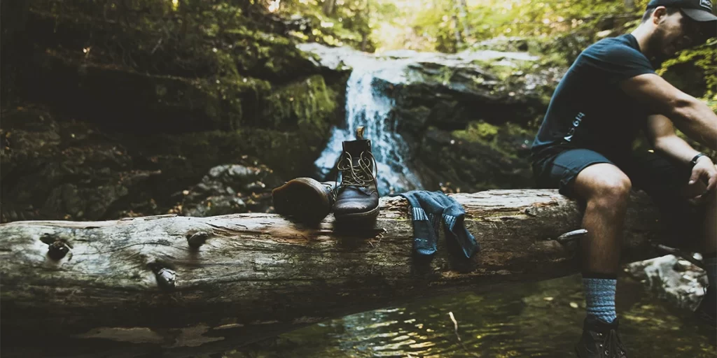 Hiking Blisters: Hiker on a log with their boots off, checking for blisters