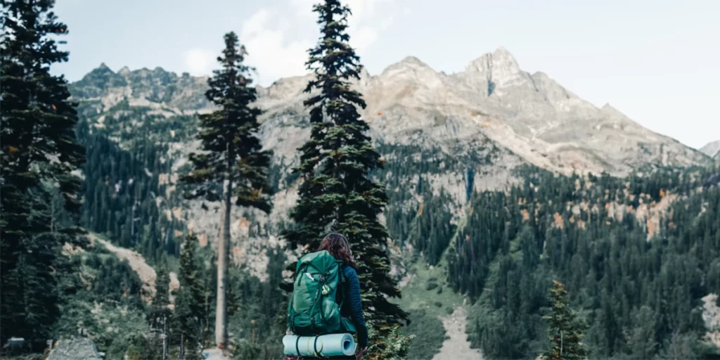 Women's Backpacks: Female backpacker wearing a medium-sized backpack and looking at a scenic mountain