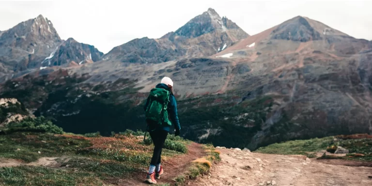 Women's Backpacks: Female backpacker wearing a medium-sized backpack walking in a valley next to mountains