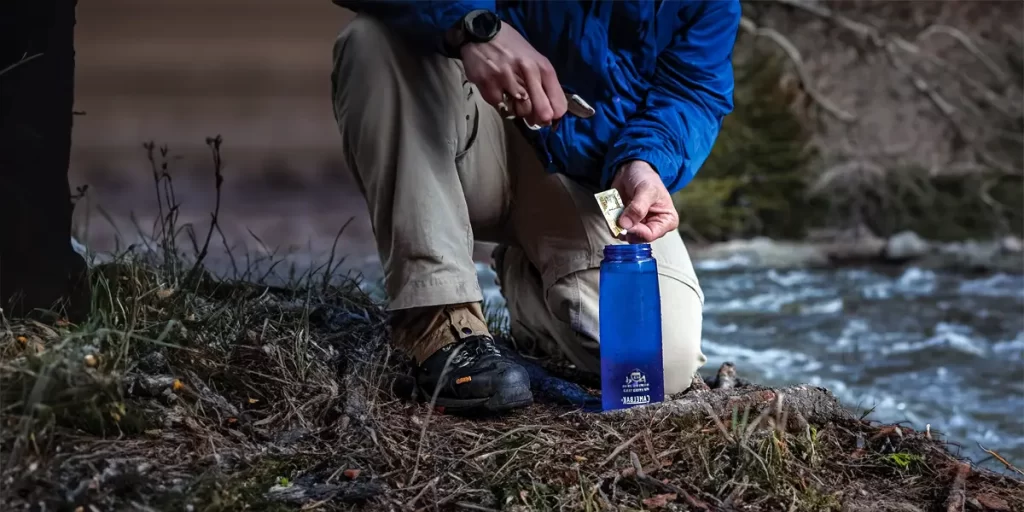 Water Purification Tablets: Hiker putting a water purification tablet in his bottle