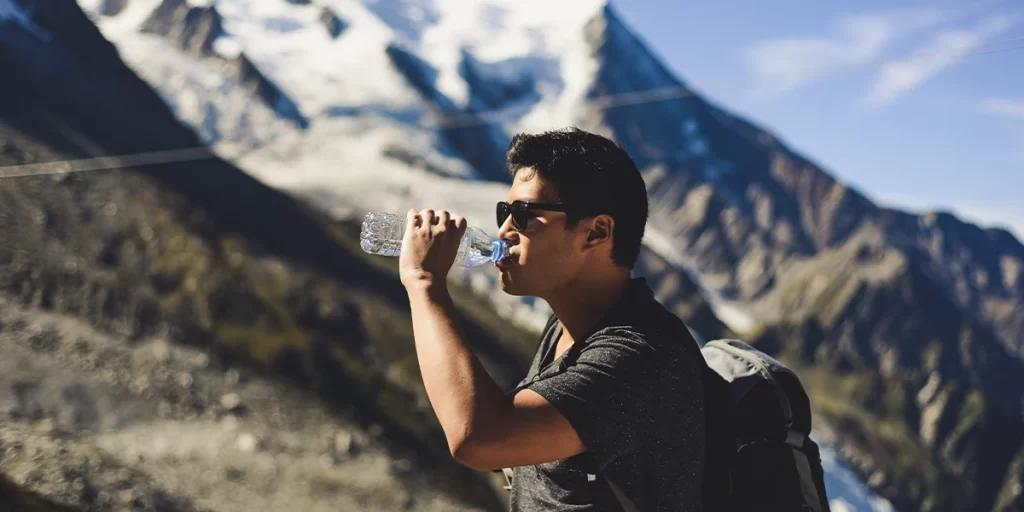Purification Tablets: Hiker drinking clean water on a scenic trail
