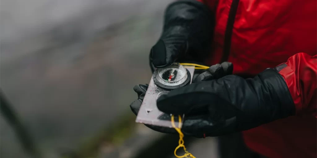 Hiking Gloves: A hiker with winter gloves holding a compass