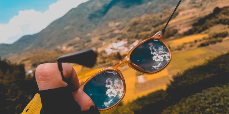 Hiking Sunglasses: A close-up of hiking sunglasses with a mountain field in the background