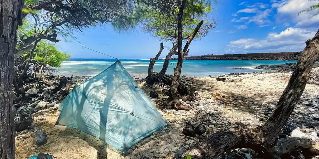 Tent Stakes: A tarp on the beach secured in sand with tent stakes and sand pitching methods