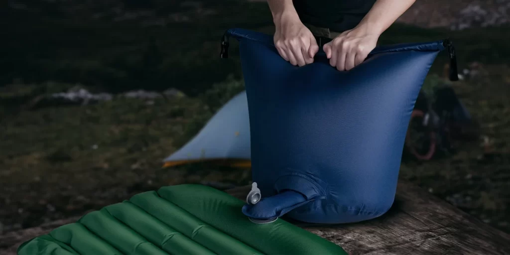 Backpacking Air Pump: A camper using a pump sack to fill up their sleeping pad
