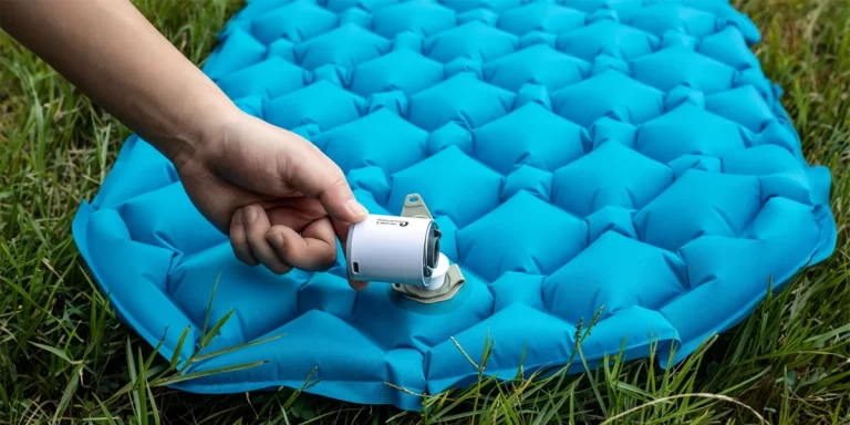 Backpacking Air Pump: Close-up of a camper using an electronic backpacking air pump to inflate their sleeping pad