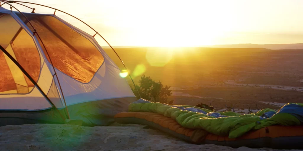 An ultralight sleeping pad next to a tent with a scenic mountain view during sunset