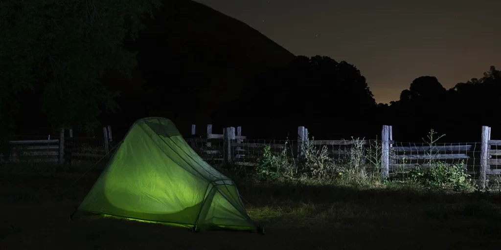 Stealth Camping: A stealthy colored tent next to a field during night