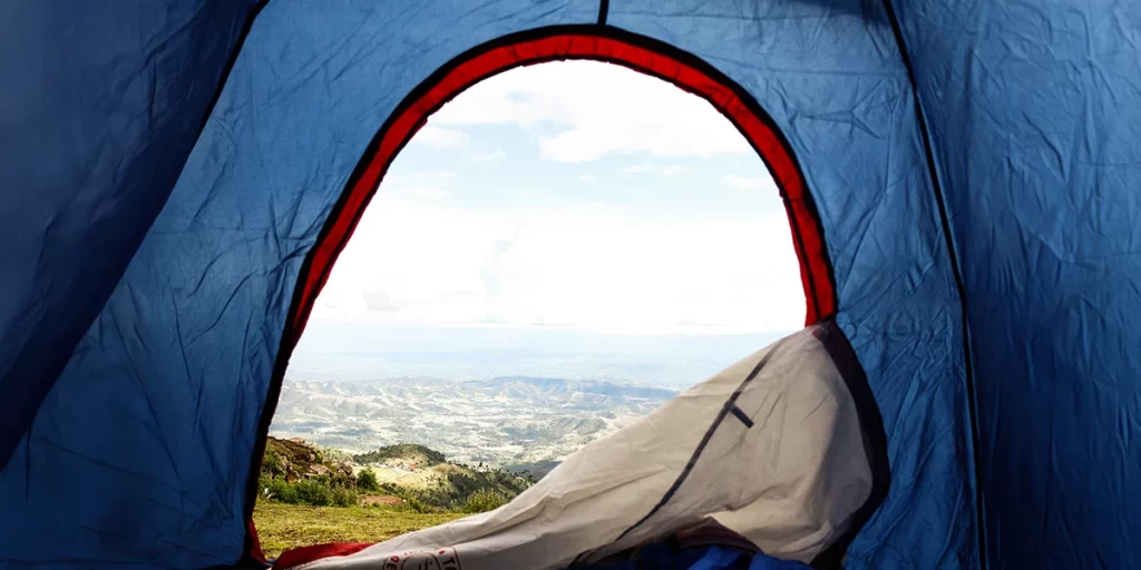 A tent with an open zipper in the mountains, a reminder of proper maintenance