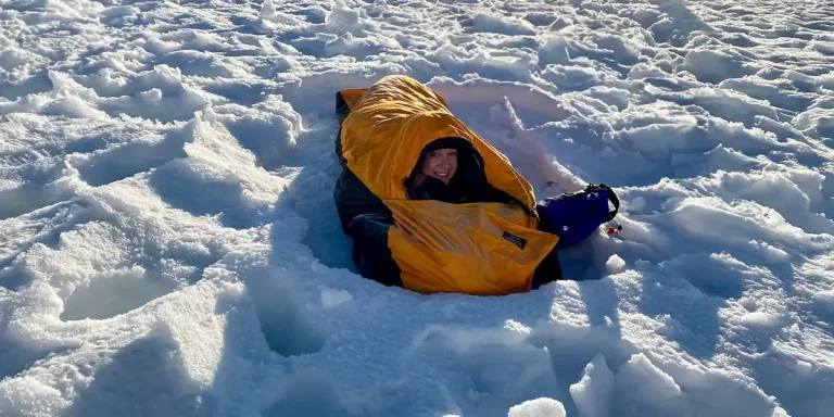 Bivy Sacks: An alpine hiker in the snow lying in her bivy sack