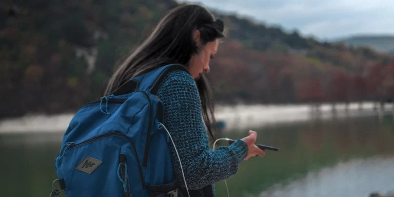 Power Banks: A backpacker is using a power bank to charge her phone while on the trail