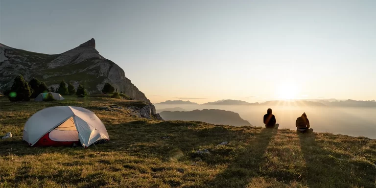 Tarp or Tent: Two campers next to their ultralight MSR tent and tarp during the golden hour, looking at mountains