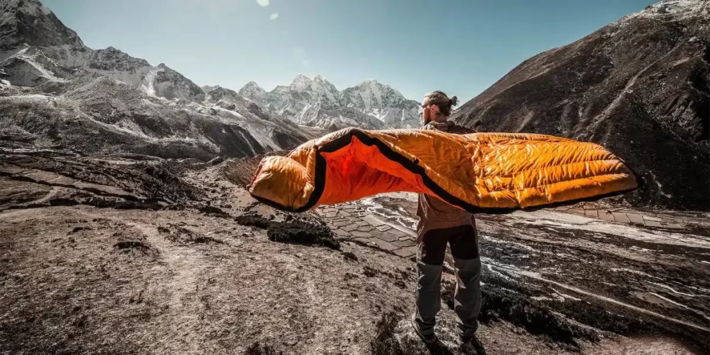 Quilts or Sleeping Bags: A person holding a quilt in a scenic mountainous high altitude region