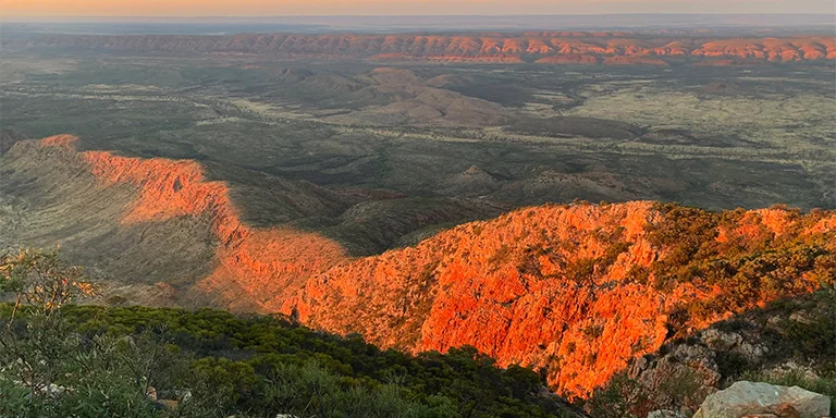 The glowing sunrise catches the rocky spur of Mount Sonder along the Larapinta Trail in Australia's Northern Territory