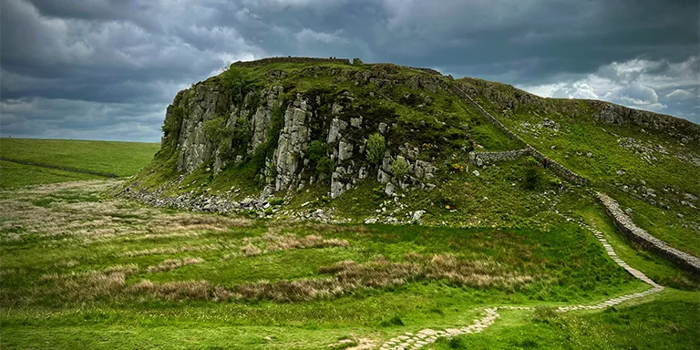 A rugged mountain path winding its way up the rocky terrain of Hadrian's Wall, evoking the essence of this ancient Roman fortification slicing across the wilderness