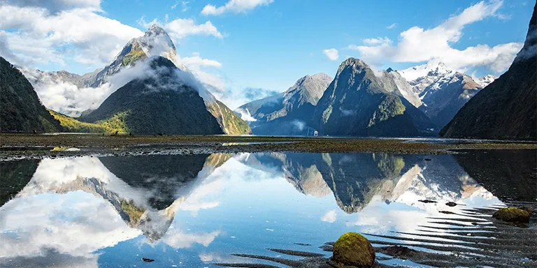 Breathtaking view of Milford Sound's serene waters perfectly reflecting the towering mountains and blue sky