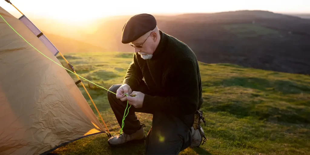 Exploring Tent Stakes: An elderly man preparing to anchor a stake on a sunny afternoon