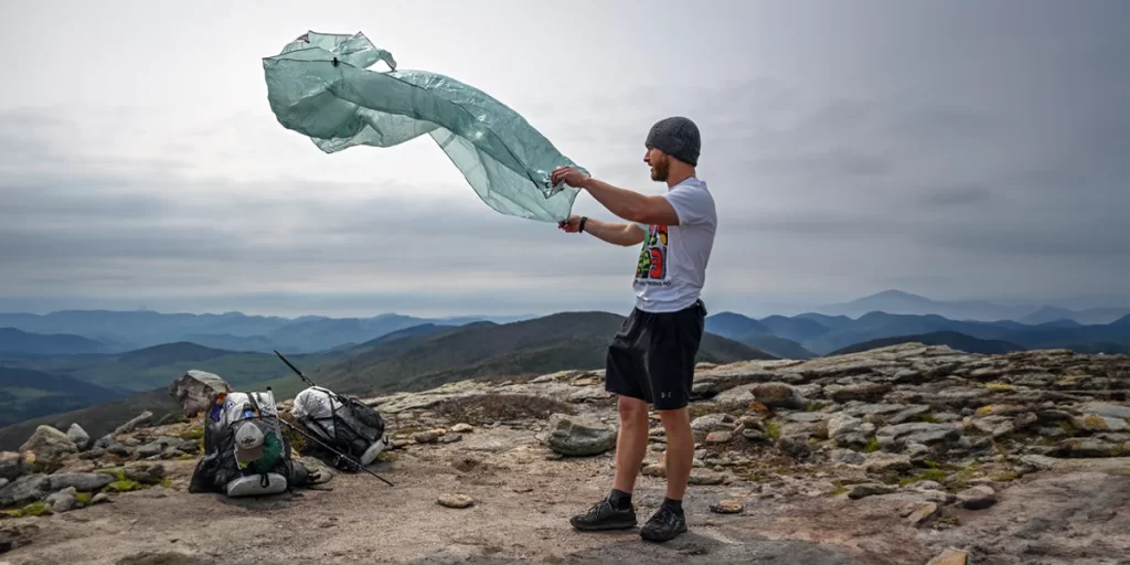 A hiker setting up a groundsheet before setting up a tarp