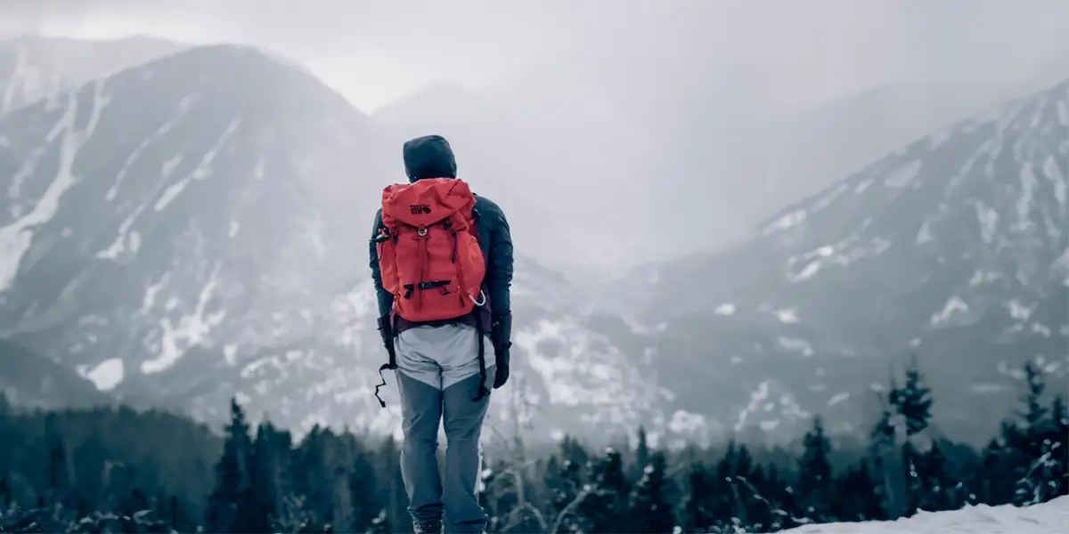 Ultralight Backpacking Gifts for Him: A man with a backpack looking at a snowy mountain range