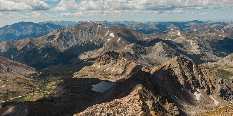 This panoramic image taken from the summit of Mount Harvard captures the dramatic line of the Collegiate Peaks mountain range stretching across the horizon in Colorado's Sawatch Range
