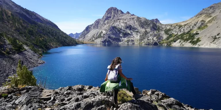 Ultralight backpacking in Idaho: A female hiker enjoys a sunny day next to a lake in Idaho