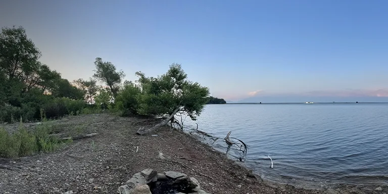 At the Hundred and Ten Mile Recreation Area, a serene evening view showcases the clear skies and tranquil waters reflecting the last rays of the setting sun