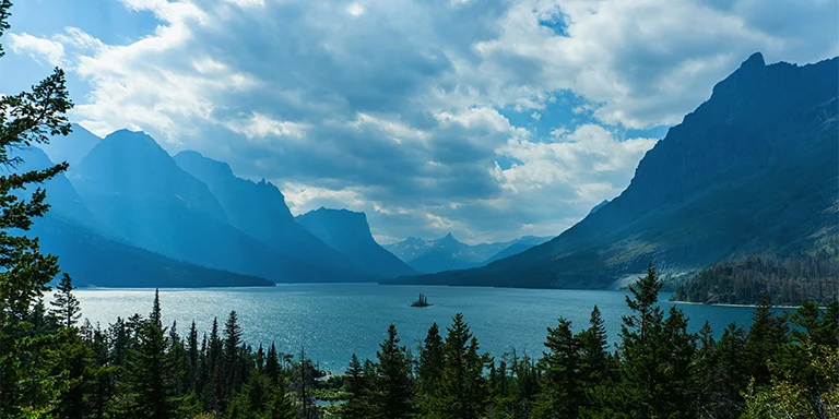 Surrounded by towering pines and jagged mountain peaks, the pristine turquoise waters of Lake Josephine mirror the rugged beauty of Glacier National Park in northwestern Montana