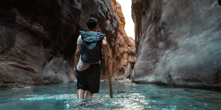 Backpacking in Utah: A man in a river, walking with a backpack
