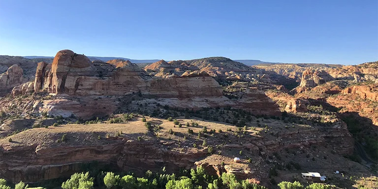 Aerial view of the Escalante River carving through rocky orange and brown canyon walls under a clear blue sky on a sunny day