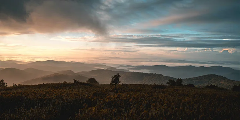 The imposing peaks of mountains are silhouetted against a vivid sunrise sky, as the first light of day crests over the distant ridges in North Carolina


