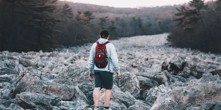 Backpacking in Pennsylvania: A hiker on a rocky trail in PA, wearing a red backpack