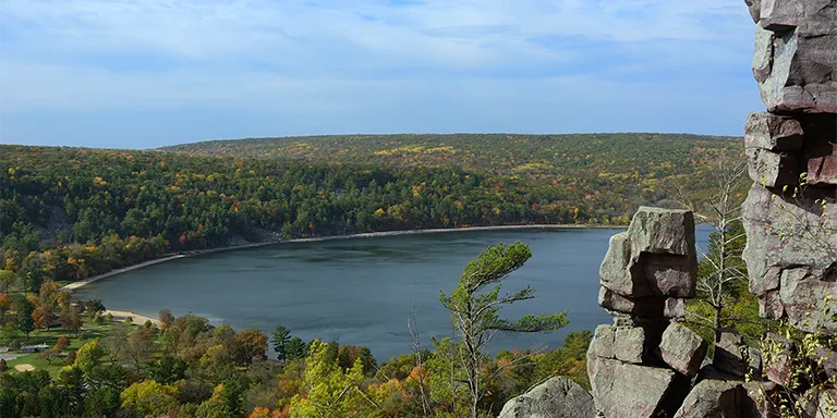 Devils Lake, surrounded by vibrant fall foliage, is a stunning autumn landscape in Devils Lake State Park near Baraboo, Wisconsin