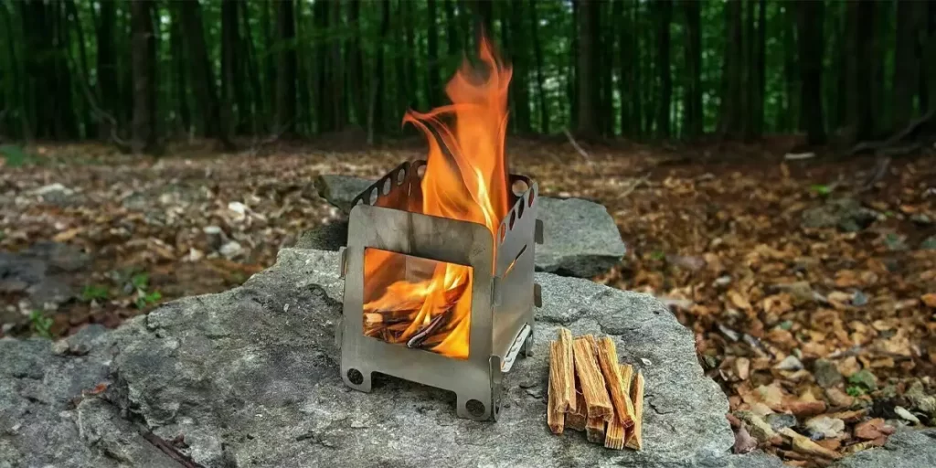 A close-up of a wood-burning stove already ablaze in a forest camp