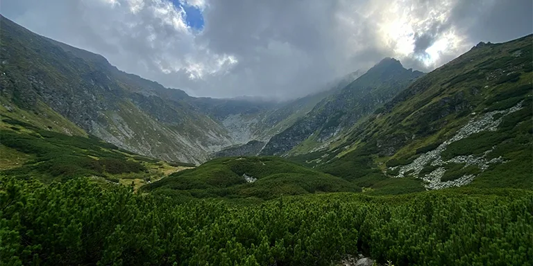 The rugged, forested peaks of Parcul National Muntii Rodnei emerge through drifting clouds, creating a mystical landscape in northern Romania