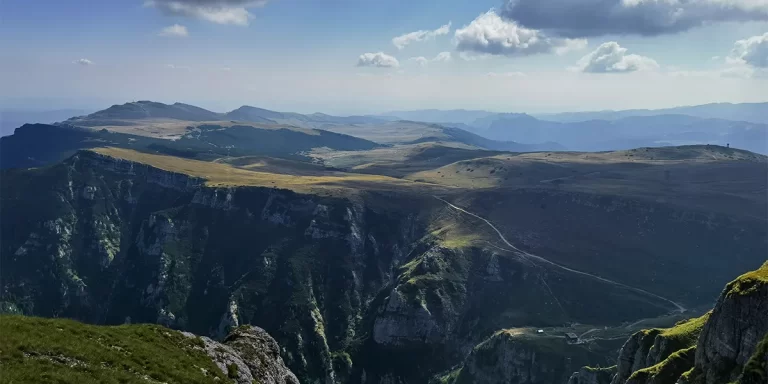 The majestic peaks of Romania's Bucegi Mountains bathed in golden sunlight on a clear blue day